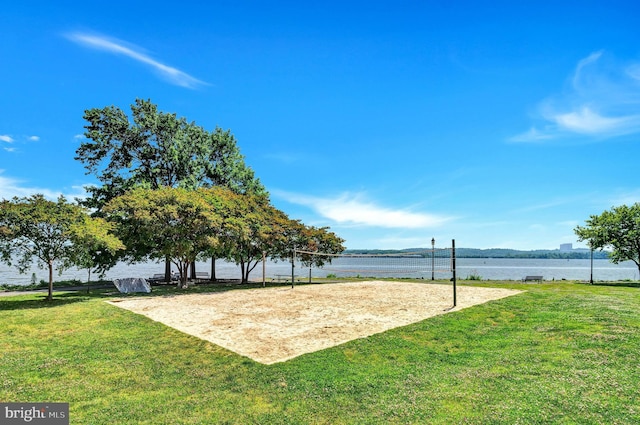 exterior space with a lawn, volleyball court, and a water view