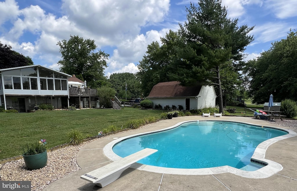 pool with stairway, a wooden deck, a diving board, a sunroom, and a lawn