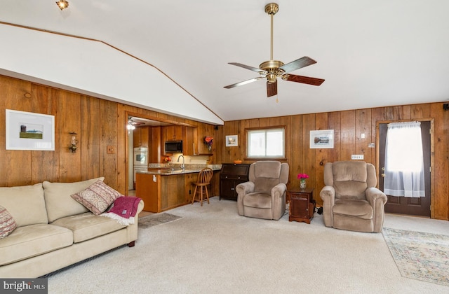 living area featuring light colored carpet, ceiling fan, wood walls, and vaulted ceiling