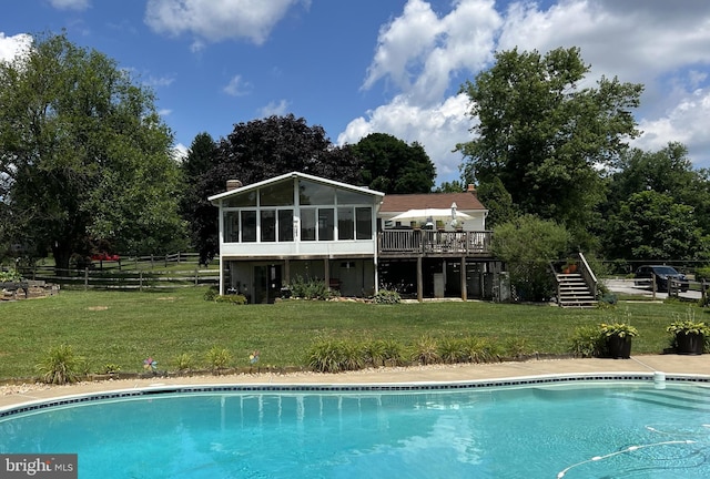 outdoor pool featuring stairway, a lawn, fence, and a sunroom