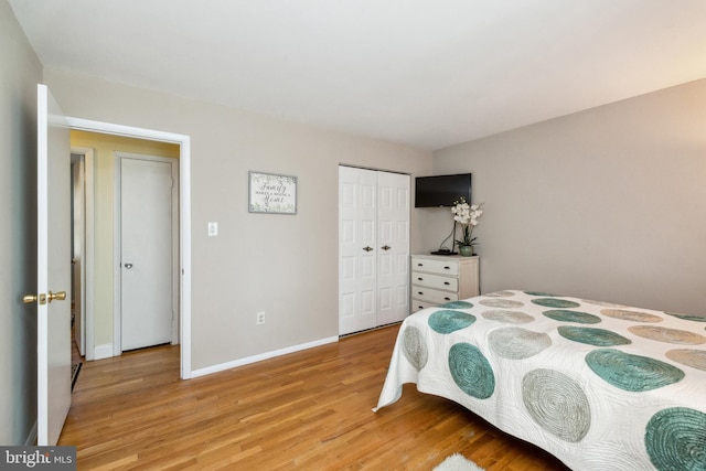 bedroom featuring light wood-style floors, baseboards, and a closet