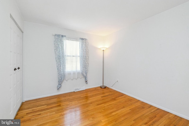 unfurnished room featuring light wood-type flooring, baseboards, and visible vents