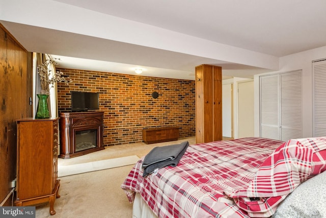 carpeted bedroom featuring a closet, a glass covered fireplace, and brick wall