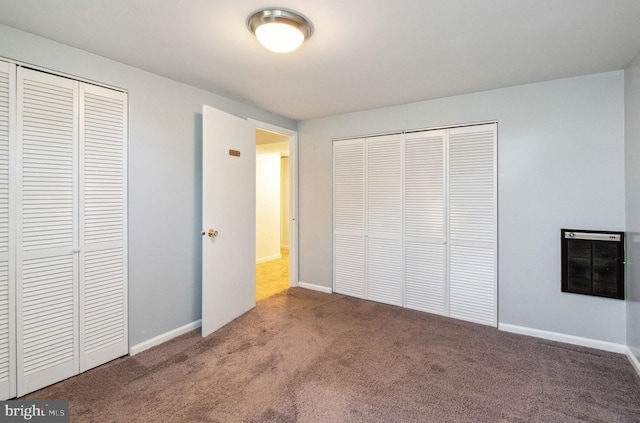 unfurnished bedroom with heating unit, a closet, baseboards, and carpet floors