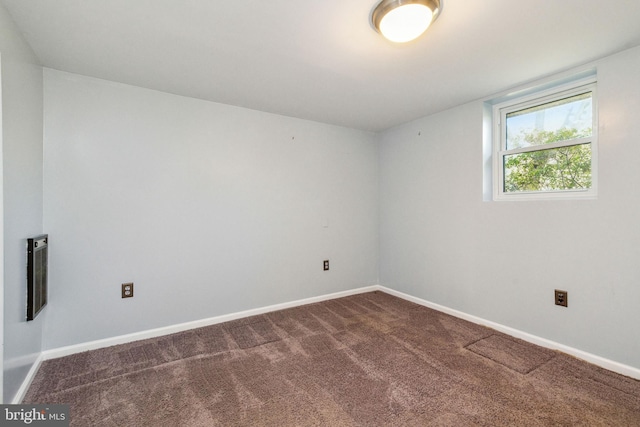 empty room with baseboards and dark colored carpet