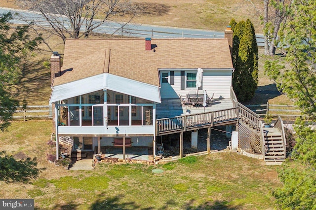 back of property featuring stairway, a wooden deck, a sunroom, a chimney, and a lawn