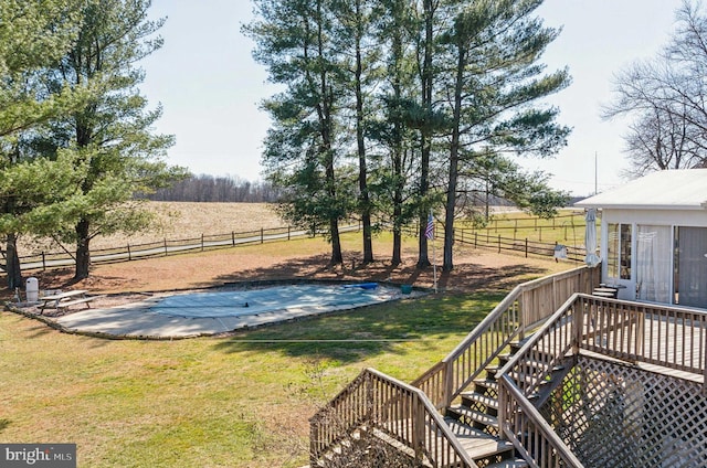 view of yard featuring fence, a fenced in pool, stairs, a rural view, and a deck