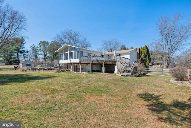 rear view of property featuring stairway, a lawn, a deck, and a sunroom