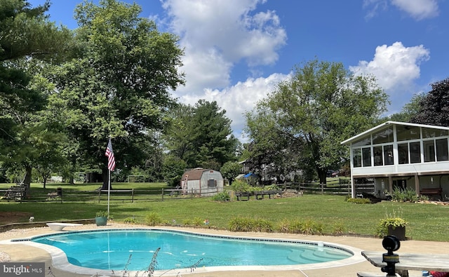 outdoor pool featuring an outbuilding, a sunroom, a yard, and fence