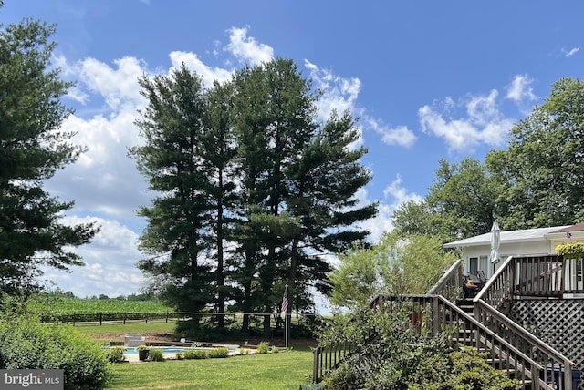 view of yard with a deck, stairway, fence, and a fenced in pool