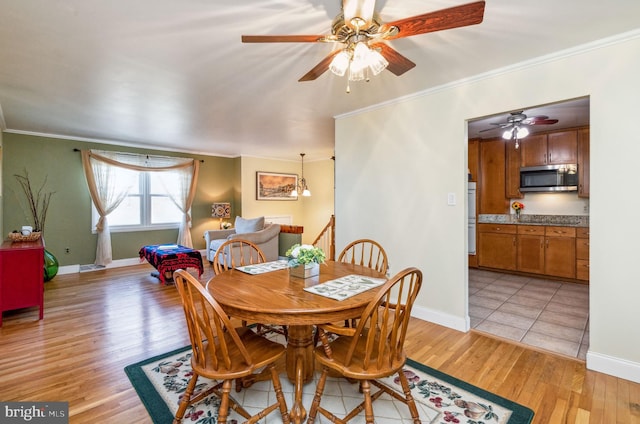 dining room with baseboards, light wood finished floors, and ornamental molding