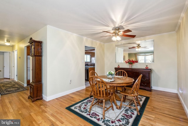 dining space featuring crown molding, light wood-type flooring, and baseboards