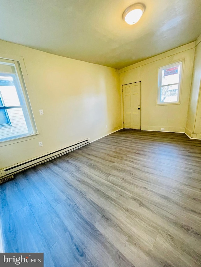 empty room with light hardwood / wood-style flooring and a baseboard radiator