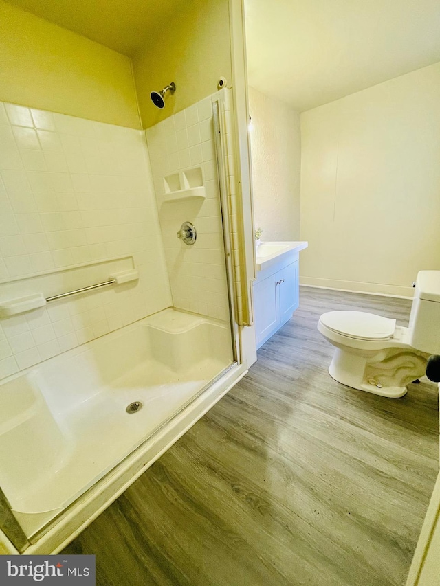 bathroom featuring vanity, hardwood / wood-style floors, a shower with shower door, and toilet