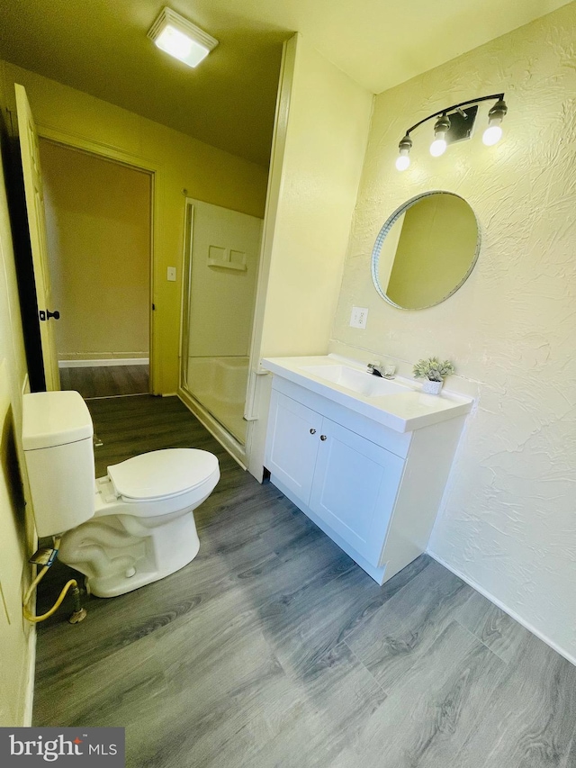 bathroom featuring hardwood / wood-style flooring, vanity, a shower, and toilet