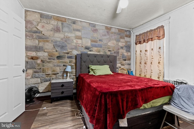 bedroom with radiator heating unit, wood finished floors, a ceiling fan, and a textured ceiling