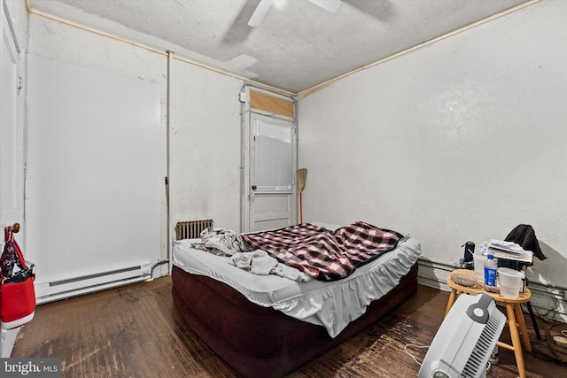 bedroom with hardwood / wood-style floors, baseboard heating, and ceiling fan