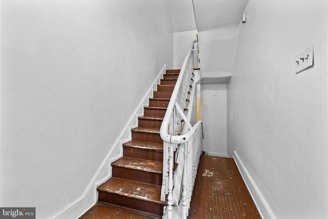 staircase with wood finished floors and baseboards
