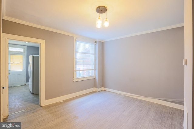 empty room with crown molding and light hardwood / wood-style floors