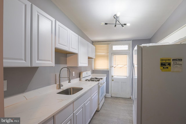 kitchen with light stone countertops, sink, white cabinets, and white appliances