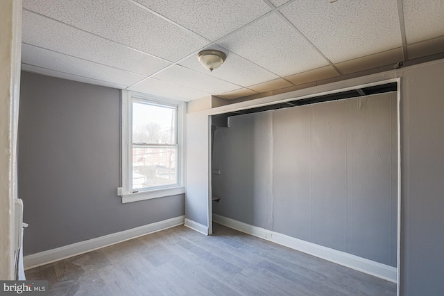 interior space featuring a drop ceiling, hardwood / wood-style flooring, and a closet