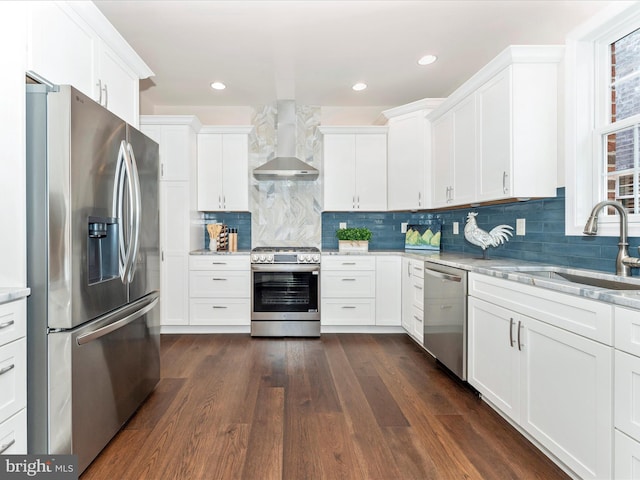 kitchen featuring white cabinetry, appliances with stainless steel finishes, sink, and wall chimney range hood