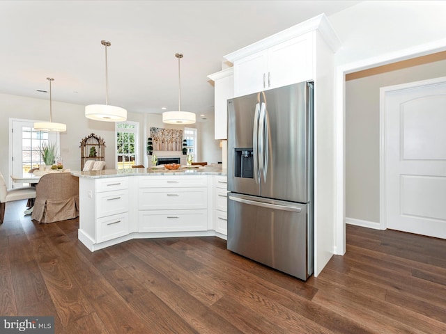 kitchen with white cabinetry, stainless steel fridge, kitchen peninsula, and hanging light fixtures