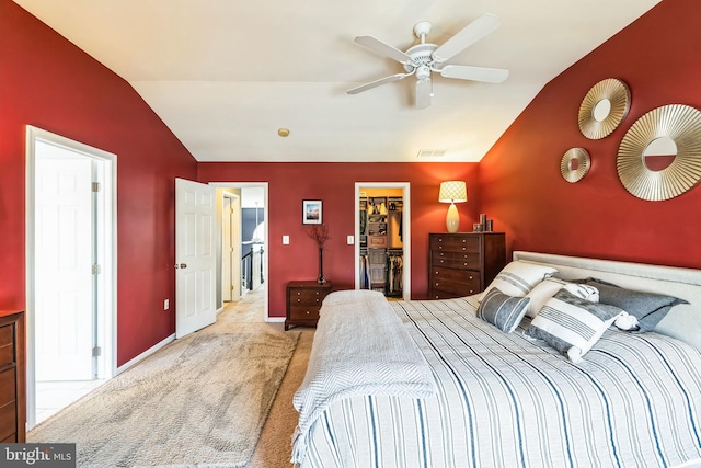 bedroom with a walk in closet, vaulted ceiling, light colored carpet, and a closet