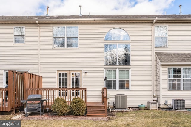 rear view of house with central AC, a lawn, and a deck