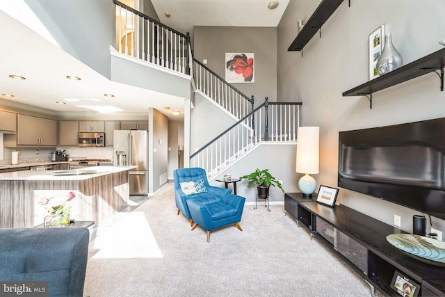 living room with a towering ceiling and light carpet