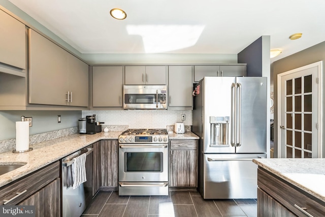 kitchen with tasteful backsplash, appliances with stainless steel finishes, and light stone counters