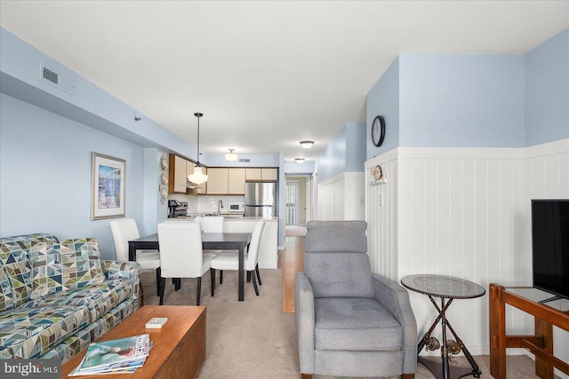 living area featuring light carpet, wainscoting, and visible vents