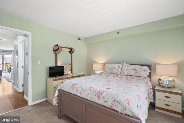 bedroom featuring baseboards, visible vents, and light colored carpet