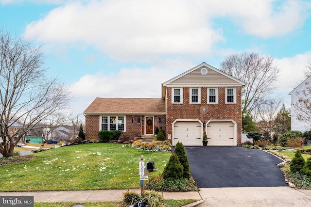 view of front of property with brick siding, a front lawn, an attached garage, and aphalt driveway