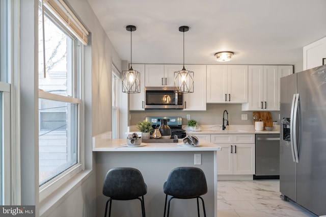 kitchen featuring white cabinetry, appliances with stainless steel finishes, sink, and a kitchen breakfast bar