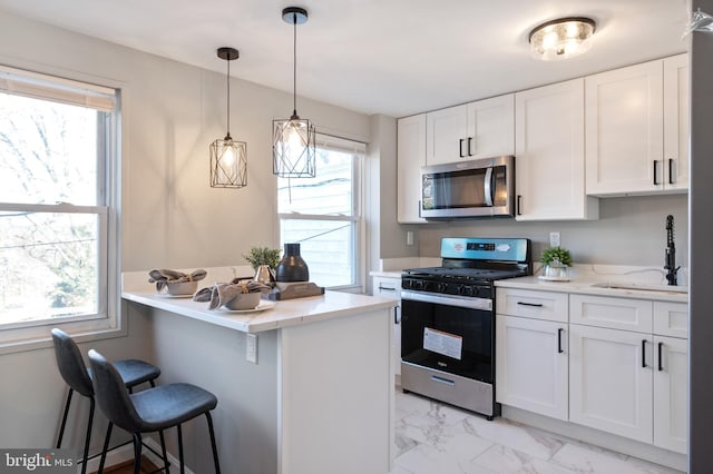 kitchen with sink, stainless steel appliances, white cabinets, and a kitchen bar