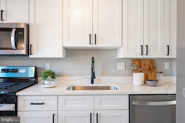 kitchen featuring light stone counters, stainless steel appliances, sink, and white cabinets