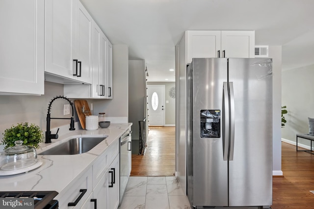 kitchen featuring light stone countertops, appliances with stainless steel finishes, sink, and white cabinets