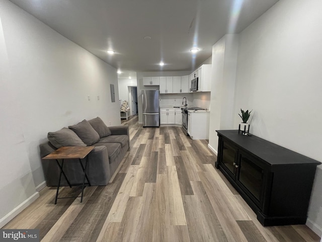 living area with light wood-style flooring, baseboards, and recessed lighting