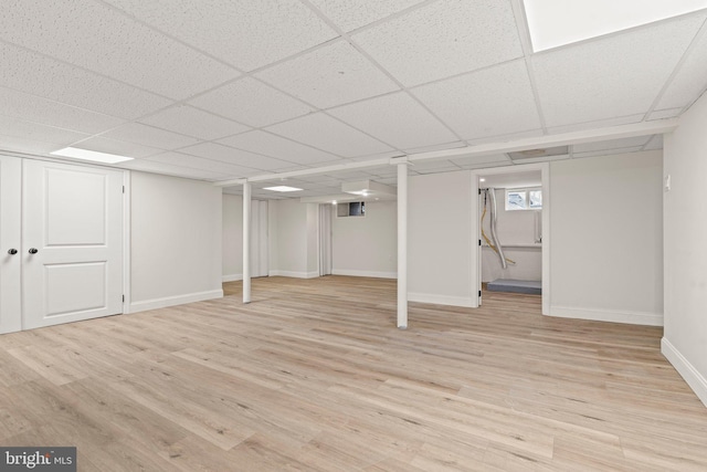 basement featuring a drop ceiling and light hardwood / wood-style flooring