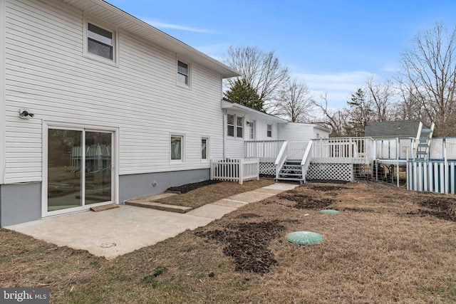 back of property with a wooden deck and a patio