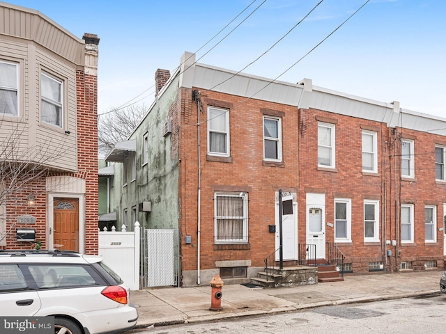 view of property featuring brick siding and fence