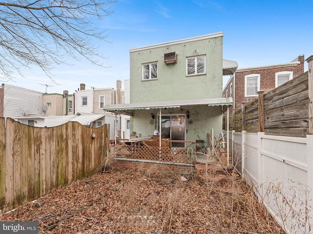 rear view of property with a fenced front yard, covered porch, and stucco siding