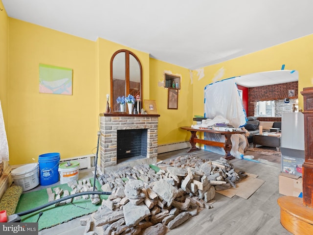 living room with baseboard heating, a fireplace, and light wood-style floors