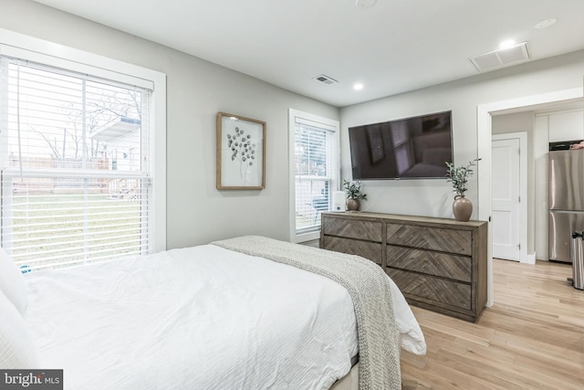 bedroom featuring stainless steel fridge and light wood-type flooring