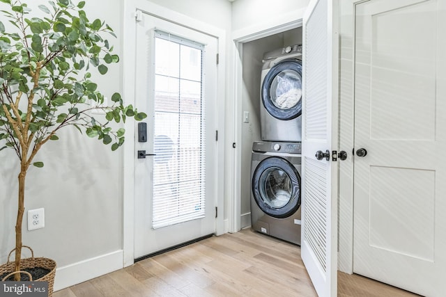 washroom featuring stacked washer / dryer, a healthy amount of sunlight, and light wood-type flooring