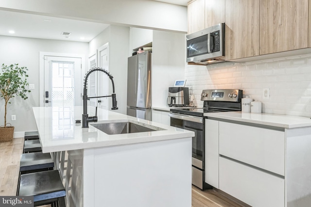 kitchen featuring stainless steel appliances, a kitchen breakfast bar, sink, and a center island with sink