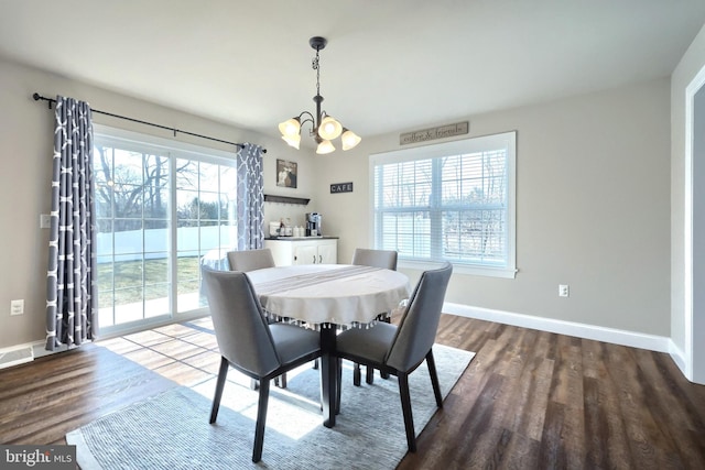 dining space featuring dark wood-type flooring and an inviting chandelier