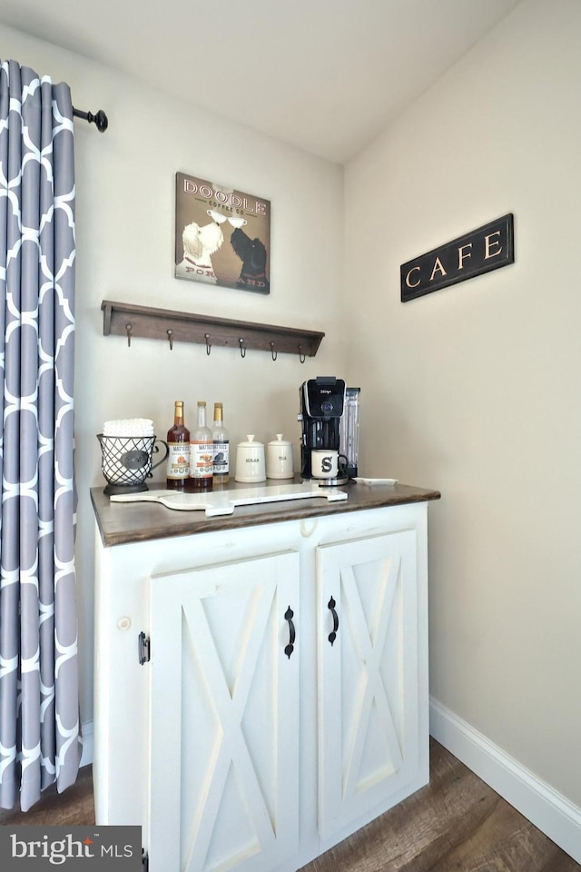 bar featuring dark hardwood / wood-style floors and white cabinets