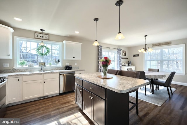 kitchen with white cabinetry, hanging light fixtures, stainless steel appliances, and a kitchen island